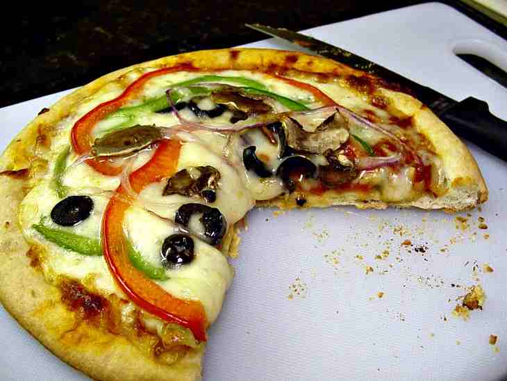 A Crispy Crust Pizza Oozing With Melted Mozzarella Cheese Topped With Black Olives, Peppers And Onions